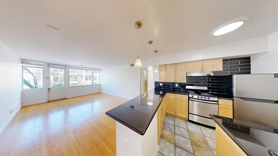 A kitchen with a black countertop and wooden floors.